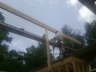 Carpenter setting a ridge beam over a new addition frame — Ice Dam Removal by Roofing Brothers in Hurdle Mills