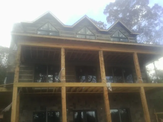 Dormers and porch framing on a large log home under construction — Roof Coating work by our crew in Hurdle Mills