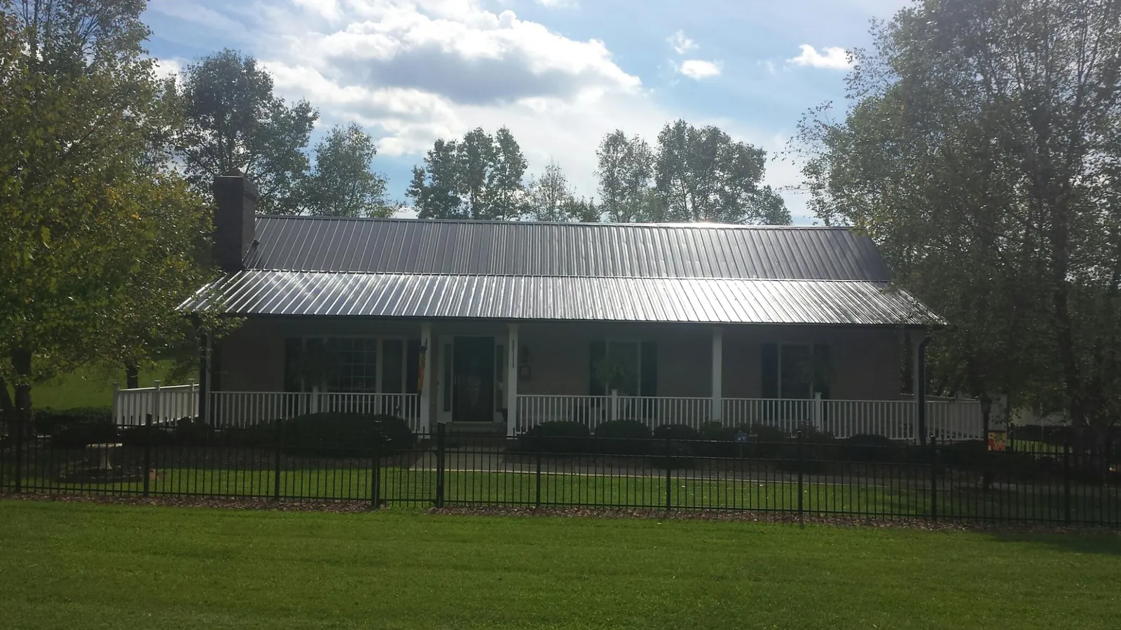 Gray metal roof on a brick ranch with a full width front porch — Gutter Guard Installation work by our crew in Hurdle Mills