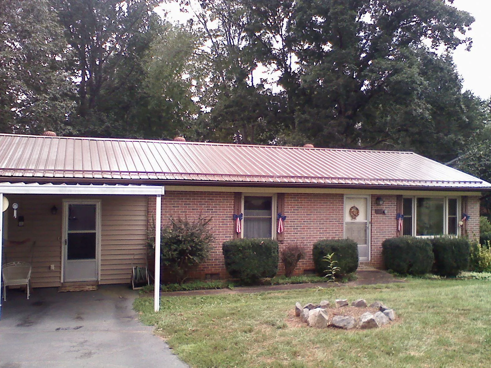 Bronze metal roof and carport on a brick ranch home — Roof Repair work by our crew in Hurdle Mills