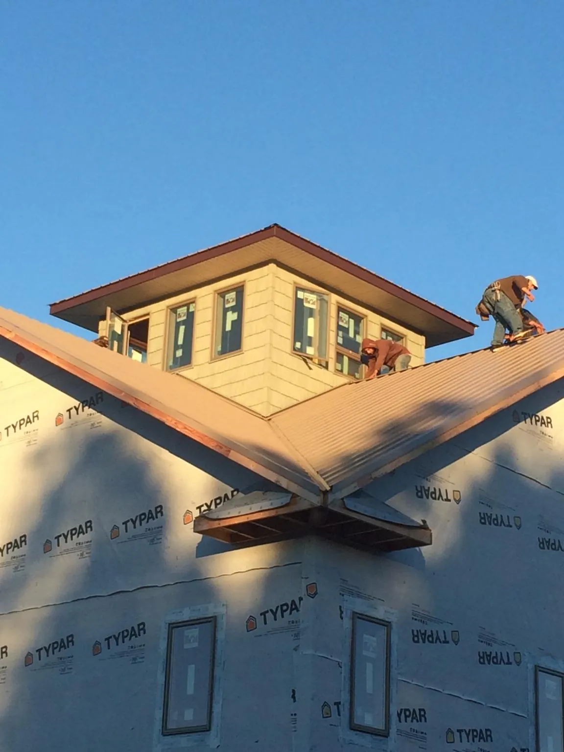 Roofers working around a rooftop cupola on a new metal roof at sunset — Roof Waterproofing in Hurdle Mills by Roofing Brothers